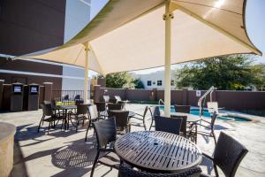奥斯汀Atwell Suites Austin Airport, an IHG Hotel的一个带桌椅的庭院和大伞