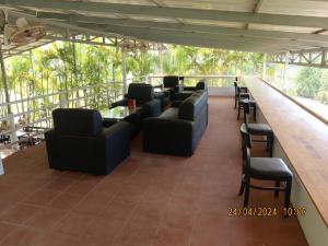 贡布Bohemiaz Resort and Spa Kampot的酒吧配有黑色沙发、椅子和柜台