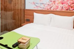 KubukUrbanview Hotel R House Batuaji的一张带绿色托盘的白色床,配有遥控器