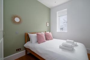 伦敦GuestReady - Chic in the heart of Kensington的卧室配有白色床和粉色及白色枕头