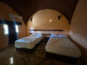 MandīshahOasis inn House的两张床位于带拱门的房间里