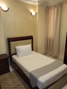 多哈Liberty Avenue Hotel的一间卧室配有一张带白色床单的床和一扇窗户。