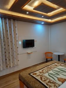 西姆拉Aagaman Woods Homestay的一间设有床铺和墙上电视的房间