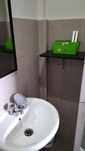 道伊斯G Hotel的浴室里的白色水槽,架子上有一个绿色的盒子