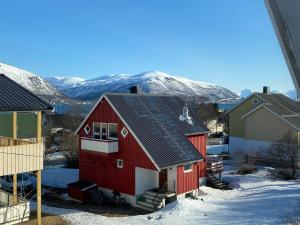 特罗姆瑟Polar Arctic Luxury House - Free parking的雪中的一个红色房子,背景是群山