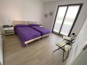 托尔博莱Casa Martinelli的一间卧室配有两张带紫色床单和椅子的床