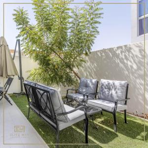 迪拜Impressive 3BR Villa-Akoya的庭院里两把椅子和一棵树