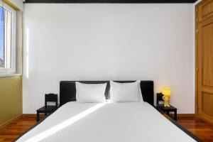 里斯本WHome Cosy Urban Hideaway in Belém with River View的卧室配有一张带两个枕头的大白色床