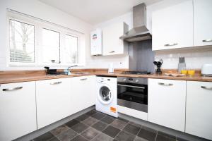 皇家伍顿巴西特Buxton Way by Tŷ SA - 3 bedroom house的厨房配有白色橱柜、洗衣机和烘干机
