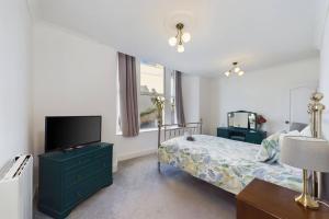 托基Loveliest Homes Torquay - 3 bed, 2 bathroom, balcony, parking的一间卧室配有一张床和一台平面电视