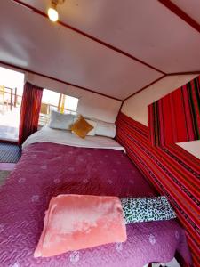 普诺Uros Titicaca UMA lodge的一张大床,位于带紫色床单的帐篷内