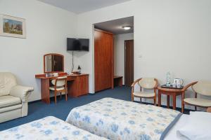 克雷尼察Hotel Jaworzyna Krynicka的酒店客房带两张床和一张桌子以及椅子。