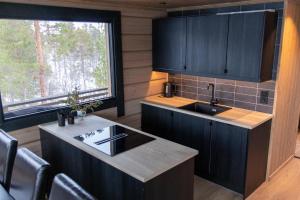 Jutulhytta的厨房配有黑色橱柜、水槽和窗户。