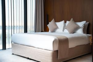 利雅德فندق الما ALMA Hotel的配有窗户的客房内的一张带白色床单和枕头的床