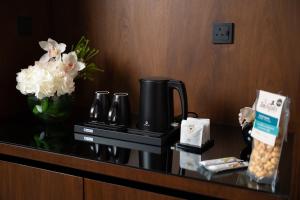 利雅德فندق الما ALMA Hotel的一张带咖啡壶和鲜花的酒店客房桌子