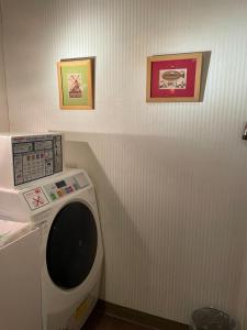 桐生市桐生爱斯酒店的浴室内配有洗衣机,墙上挂有两张照片