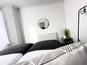 伦敦Serviced 4 bed 2 bath Manor Park House的卧室配有黑白床和镜子