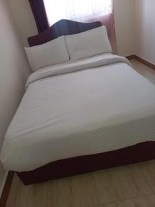 Langata RongaiTom's Breeze的一张带白色床单和枕头的床