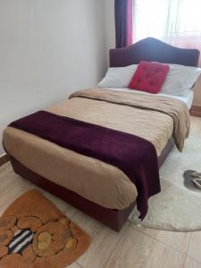Langata RongaiTom's Breeze的一张床上铺有紫色毯子和红色枕头