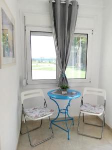 奥林匹亚达Semeli Ancient Stagira 4 Apts Chalkidiki的窗户间里一张蓝色的桌子和两把椅子