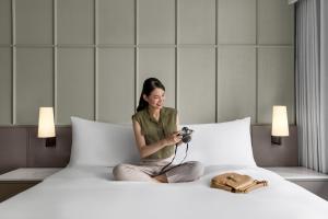 曼谷 曼谷素坤逸20号万怡酒店的坐在床上拿着摄像头的女人
