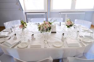 伊兹林根因泽灵根瓦瑟尔城堡餐厅&酒店的白色的桌子,上面有白色的板子和鲜花