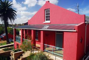 NapierThe Restio Country Guesthouse的红色的房子,有窗户和棕榈树