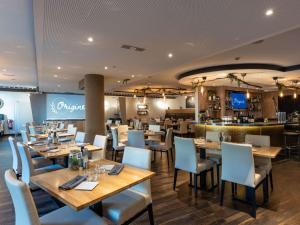 卢森堡卢森堡中心诺富特酒店的一间带木桌椅的餐厅和一间酒吧