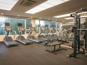 西归浦市Mercure Ambassador Jeju的健身房设有一排健身自行车和跑步机
