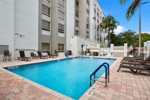 韦斯顿Hampton Inn Weston Fort Lauderdale的一座带椅子的游泳池以及一座建筑