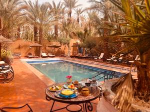 扎古拉Riad le petit jardin的游泳池旁的餐桌上放着食物