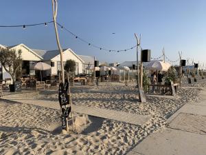 诺德克豪特Het Oude Raadhuis的沙滩上配有桌子、遮阳伞和椅子
