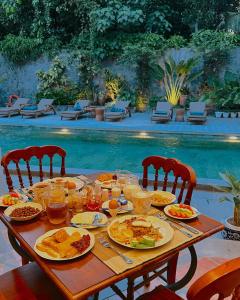 日惹Dandaman villa的一张桌子,上面有盘子,放在游泳池边