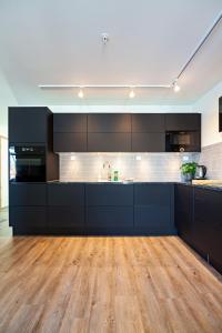 巴尔斯塔Gjermesøy Luxury Apartment的一间铺有木地板的大型厨房,配有黑色橱柜
