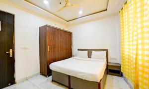 新德里FabExpress The Maharaja Grand的一间卧室配有一张床和一个木制橱柜