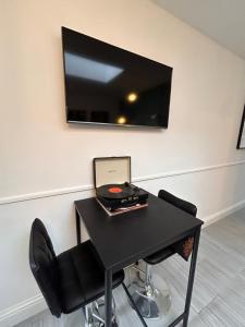 伯明翰Vibrant Bungalow 2 Bedroom Flat with secure private parking的一张带笔记本电脑的黑桌和墙上的电视