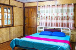 彭世洛Ruenpakkiangnan เรือนพักเคียงน่าน的一间卧室配有一张带蓝色枕头的床和窗帘