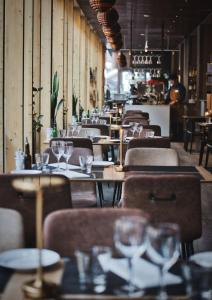 斯德哥尔摩比列雅居酒店的餐厅设有木桌和椅子,配酒杯
