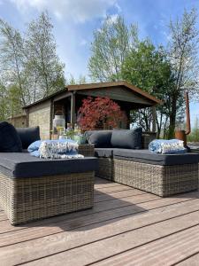芬克芬Luxury Experience in Off The Grid Lodge at an Amazing Lake Vinkeveense Plassen的两个柳条长椅,坐在带凉亭的甲板上