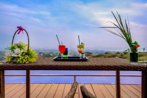 伊加特普里Wabi Sabi Resort, Igatpuri的甲板上一张桌子,上面有两杯饮料