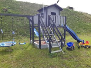 吉日茨科Letnisko Skarpa的一个带滑梯和玩具的草地游乐场