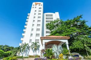 圣玛尔塔GHL Relax Hotel Costa Azul的一座高大的白色建筑,前面设有一个凉亭