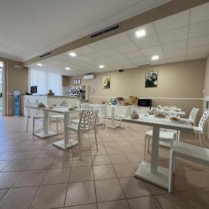 圣乔瓦尼·罗通多想象酒店的用餐室配有桌子和白色椅子