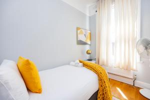 伦敦6 Bedroom House by AV Stays Acton Sleeps 11 Free Parking的卧室配有白色床、黄色枕头和窗户