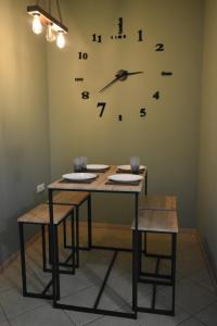 卡瓦拉Natalia guest house的一张桌子、两把椅子和墙上的时钟