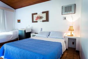 圣佩德罗-达阿尔德亚Pousada Pontal da Praia的一间卧室配有一张带蓝色棉被的床