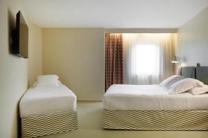 戛纳Hotel des Victoires的酒店客房设有两张床和窗户。