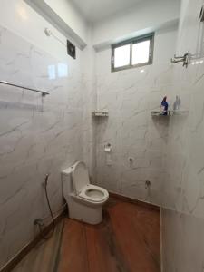 阿加尔塔拉Ujjayanta Homestay的白色的浴室设有卫生间和窗户。