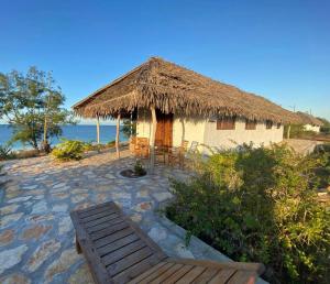 MossurilNamahamade Lodge Restaurante & Beach Bar的茅屋,长凳和茅草屋顶