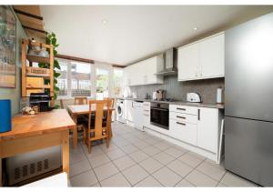 伦敦chic 3-BR home welll located in Islington的厨房配有白色橱柜和桌子